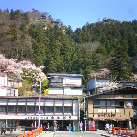 駅前の橋から山寺を見上げる