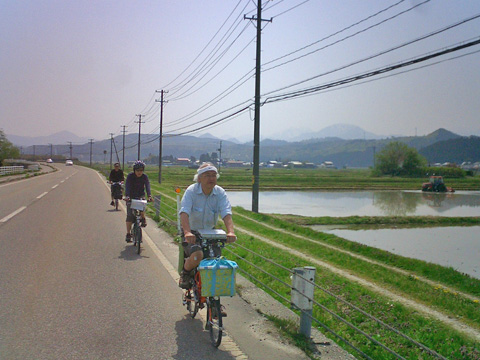 田植え中の田んぼの脇を行く